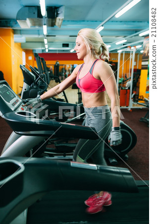 Athletic girl adjusting the treadmil in gym 21108482