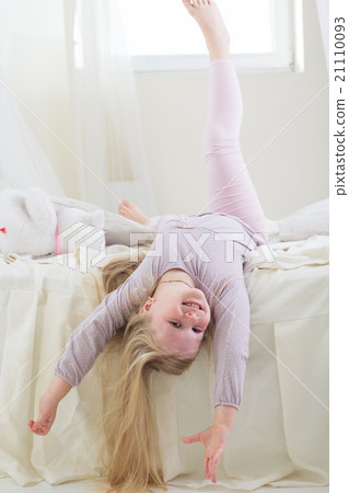 Happy cute child girl lying barefoot in the bed 21110093