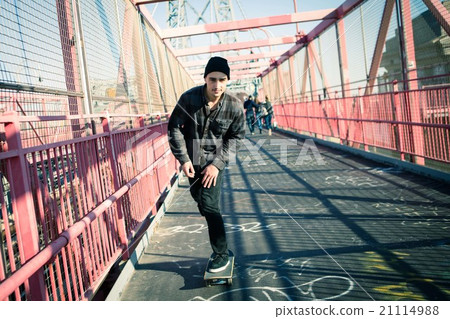 Young male skateboarder cruising on bridge 21114988