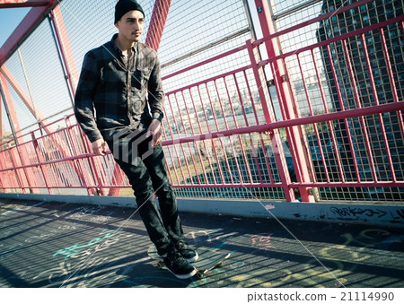 Young male skateboarder cruising on bridge 21114990