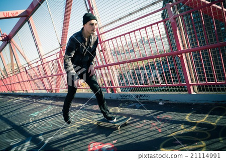 Young male skateboarder cruising on bridge 21114991