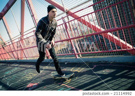 Young male skateboarder cruising on bridge 21114992