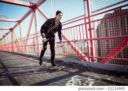 Young male skateboarder cruising on bridge 21114995