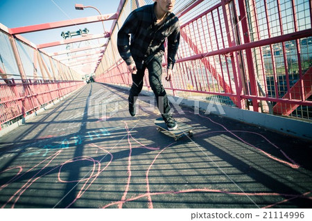 Young male skateboarder cruising on bridge 21114996