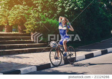 Female cyclist rides a racing bike on road Female cyclist rides a racing bike on road 21124266