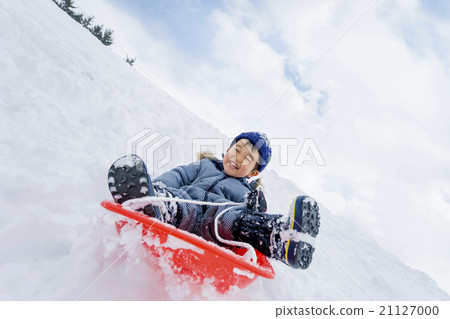一個男孩在雪地公園玩雪橇 21127000