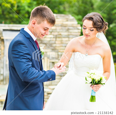 groom and bride is wearing a ring on the finger 21138142
