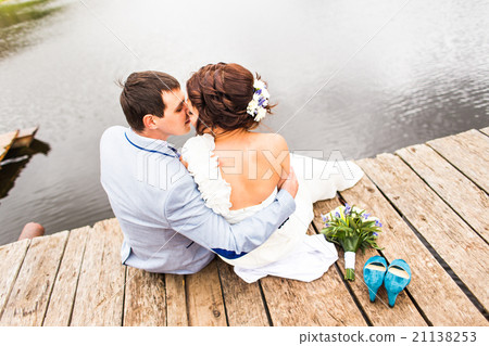 Beautiful young wedding couple sitting on the pier Beautiful young wedding couple sitting on the pier 21138253
