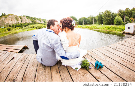 Beautiful young wedding couple sitting on the pier Beautiful young wedding couple sitting on the pier 21138254