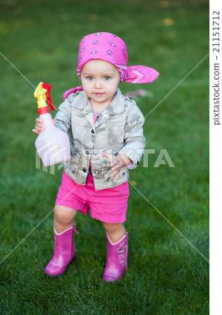 Happy baby girl in red boots walking on the meadow 21151712