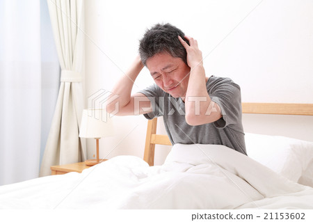 Mature men holding their heads in bed 21153602