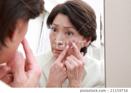 60多歲的女性用鏡子檢查皮膚 21159716
