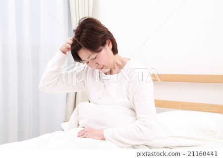 Mature age lady holding a head in bed 21160441