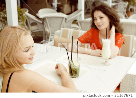 portrait of two pretty modern girl friends in cafe 21167671
