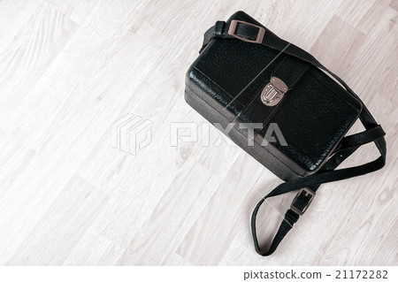 Vintage black leather case on a wooden floor 21172282