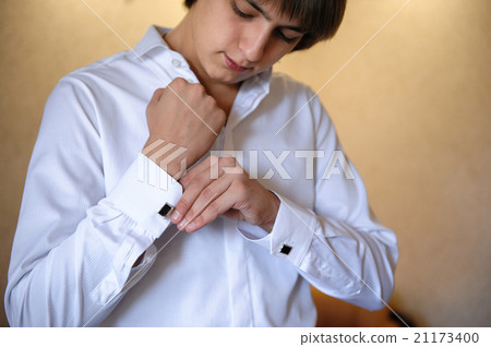 groom wears cuff links on white shirt 21173400
