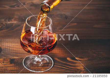 Pouring brandy or cognac from the bottle  21185050