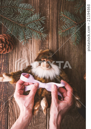 Tying violet ribbon on a monkey  toy vertical 21194868