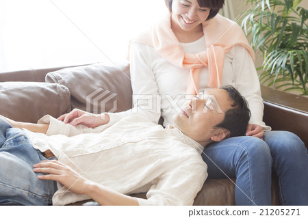 A man sleeping at ease and a woman sitting on the sofa A man sleeping at ease and a woman sitting on the sofa 21205271