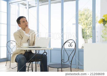 A man who uses a personal computer at a cafe A man who uses a personal computer at a cafe 21208609