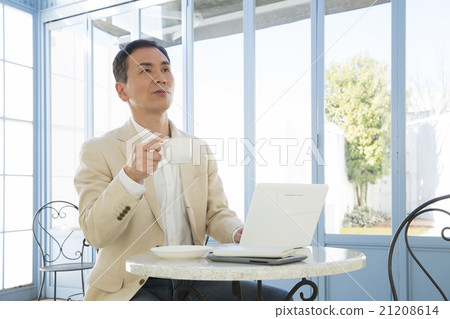 A man who uses a personal computer at a cafe A man who uses a personal computer at a cafe 21208614