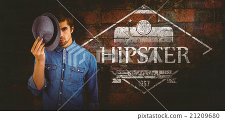 Composite image of portrait of hipster holding hat in front of f Composite image of portrait of hipster holding hat in front of f 21209680