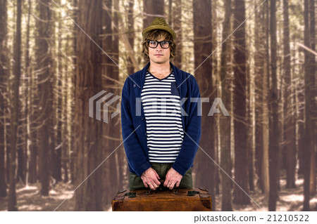 Composite image of serious hipster holding a suitcase 21210522