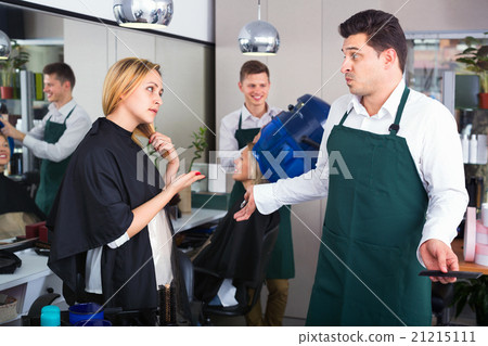 woman blaming hairdresser in bad haircut 21215111