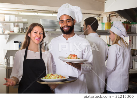 Waitress and crew of professional cooks posing at restaurant Waitress and crew of professional cooks posing at restaurant 21215300