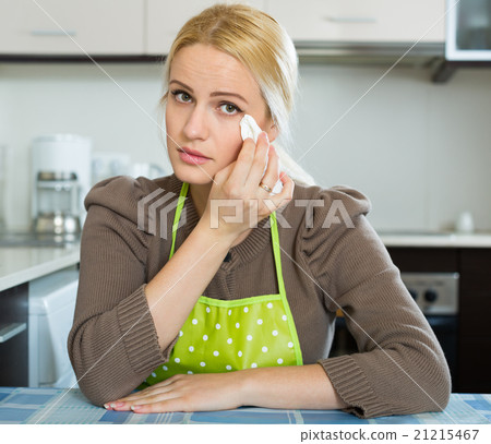 Sad woman sitting at kitchen Sad woman sitting at kitchen 21215467