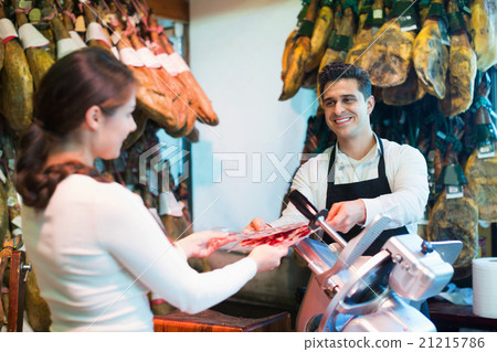Young cheerful brunette choosing iberico and serrano jamon 21215786