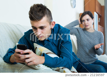 son playing with phone, mother trying to talk son playing with phone, mother trying to talk 21216597