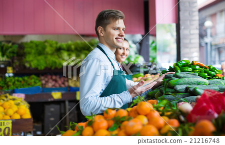 Friendly sellers having vegetables and fruits on displays Friendly sellers having vegetables and fruits on displays 21216748