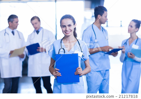 Female doctor holding medical report and smiling at camera Female doctor holding medical report and smiling at camera 21217818