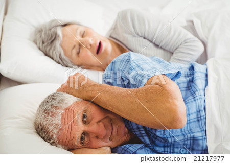 Senior man covering her ears while man snoring 21217977