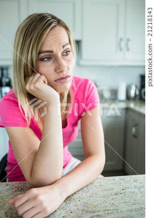 Thoughtful blonde woman leaning on her counter Thoughtful blonde woman leaning on her counter 21218143