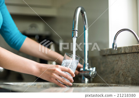 Pretty blonde woman filling a glass of water Pretty blonde woman filling a glass of water 21218380