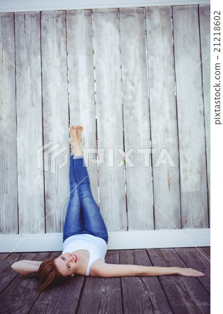 smiling hipster woman with her legs against the wall 21218602