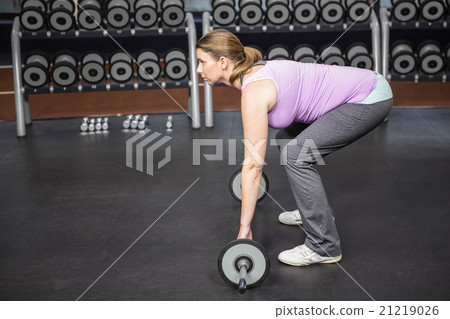 Determined woman lifting barbell 21219026