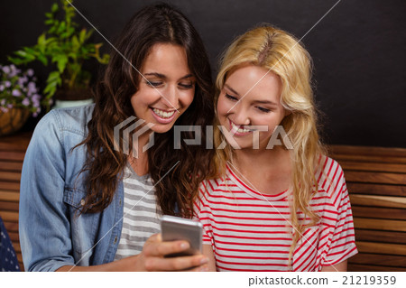 Smiling friends watching a smartphone together 21219359