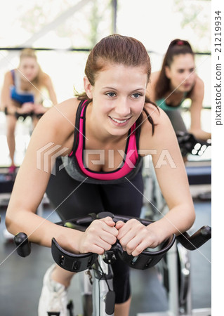 Fit group of people using exercise bike together 21219934