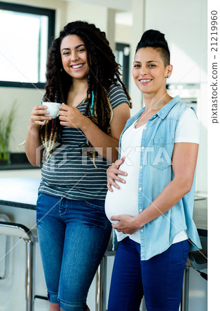Portrait of pregnant lesbian couple standing together 21219960