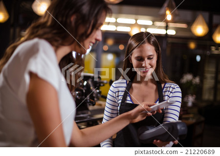 Smiling woman paying with smartphone 21220689