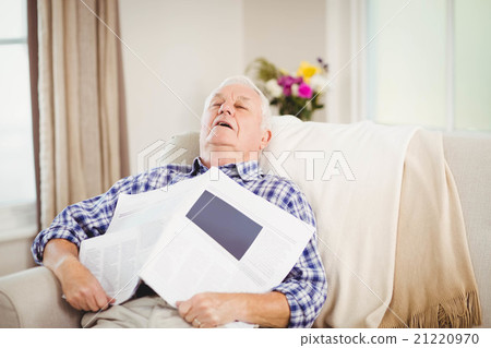 Senior man relaxing on sofa with newspaper Senior man relaxing on sofa with newspaper 21220970