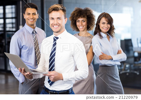 Businessman standing with a laptop and team standing in backgrou 21220979