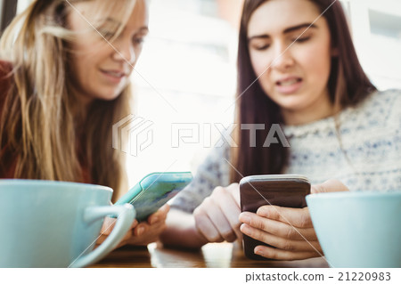 Friends using smartphone and having coffee Friends using smartphone and having coffee 21220983