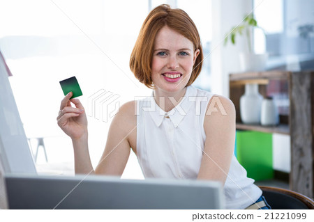 smiling hipster business woman holding up a credit card 21221099