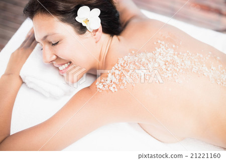 Woman lying on massage table with salt scrub on back Woman lying on massage table with salt scrub on back 21221160
