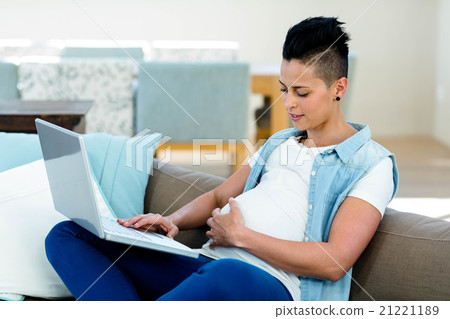 Pregnant woman relaxing on sofa with her laptop 21221189