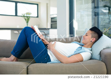 Pregnant woman reading a book while lying on sofa 21221190